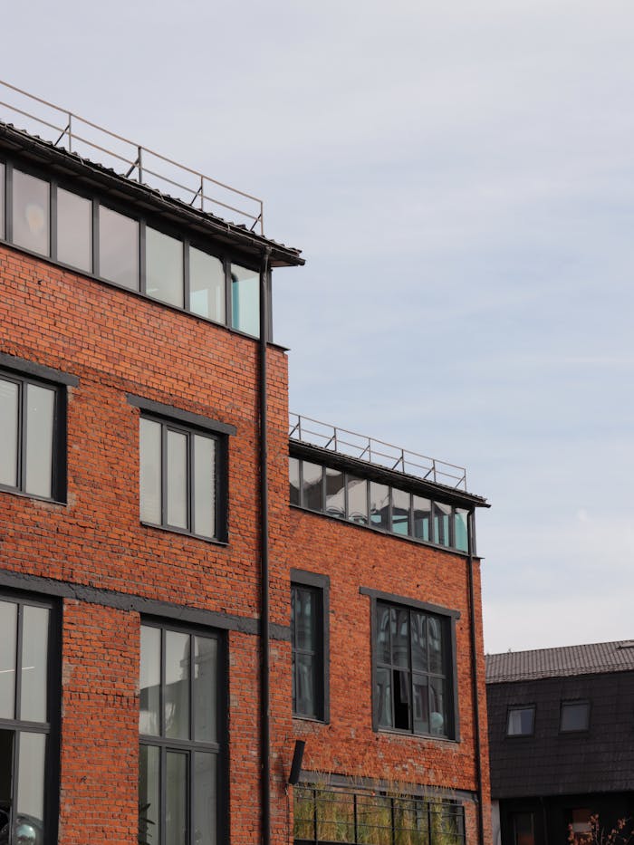 Contemporary architecture featuring a red brick facade with large glass windows and a clear sky.