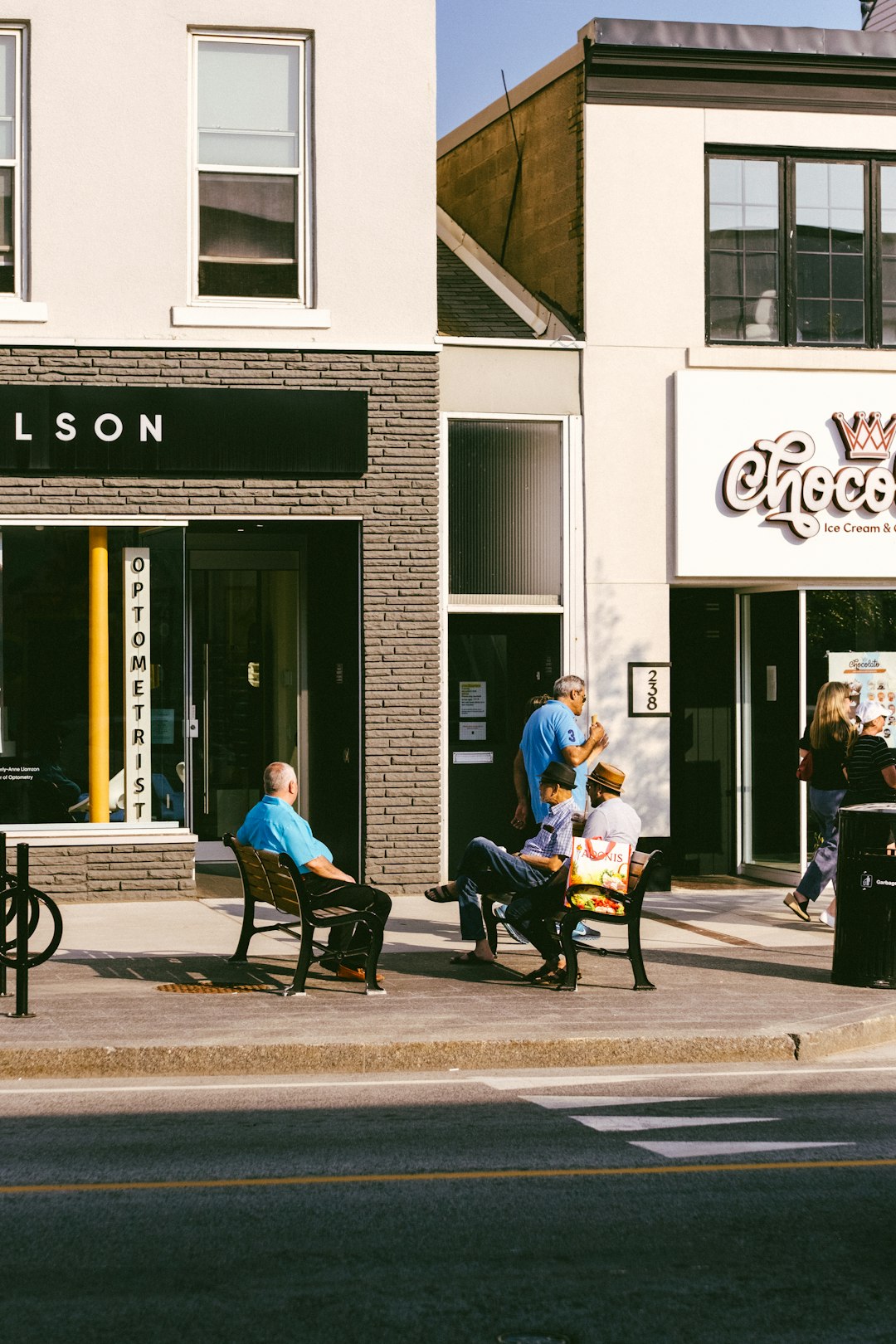 people-sitting-on-benches-outside-shops-on-a-sunny-day-3-w11uf9j4i